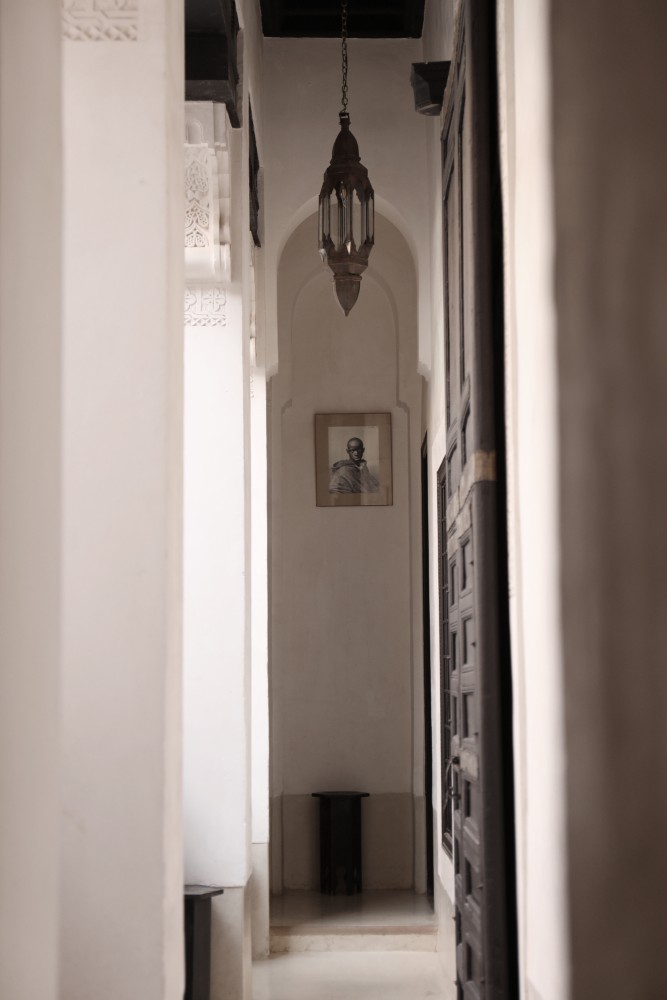 L'enfilade du Riad Azzouna 13, lanterne suspendue et portrait encadré au bout du couloir — les derniers pas de l'arrivée