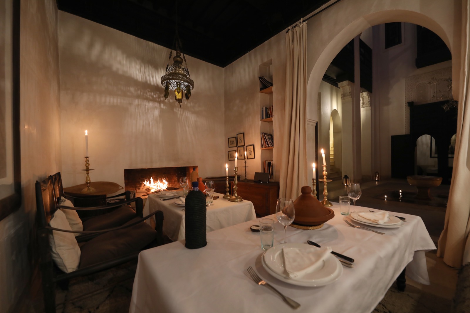 Le salon à cheminée du Riad Azzouna 13 au soir &mdash; feu allumé, tables dressées aux chandelles sous la lanterne